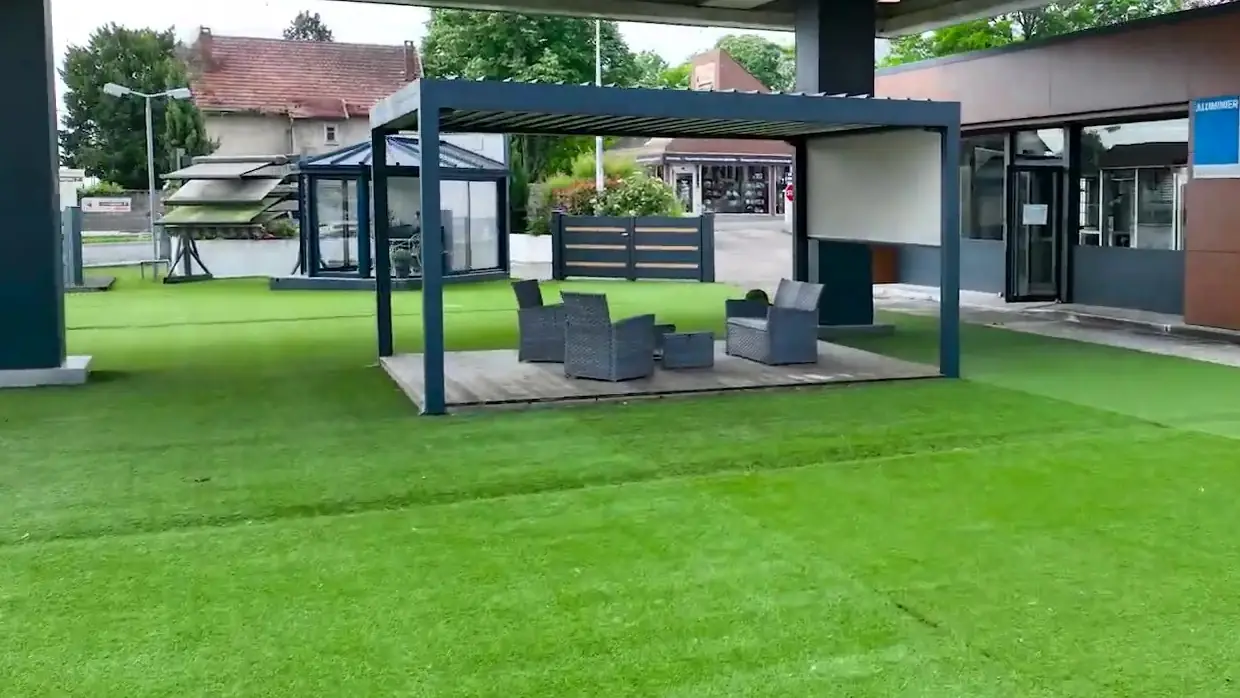 Exposition extérieure d’Alu Glace à Saint-Doulchard : pergola avec salon de jardin, véranda, stores et clôtures sur gazon